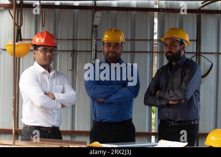 Portrait of male engineers team at construction site. Experienced confident architects with arms crossed. Construction Industry Development Council Stock Photo