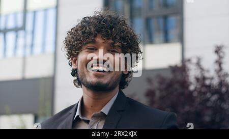 Portrait in city outdoors Indian man business specialist smiling toothy happy laughing businessman Arabian male guy entrepreneur laugh humorous smile Stock Photo