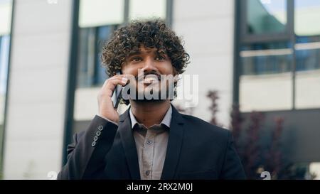 Close up smiling Indian male Arabian guy Hispanic happy ethnic man businessman entrepreneur manager business worker professional in city talk Stock Photo