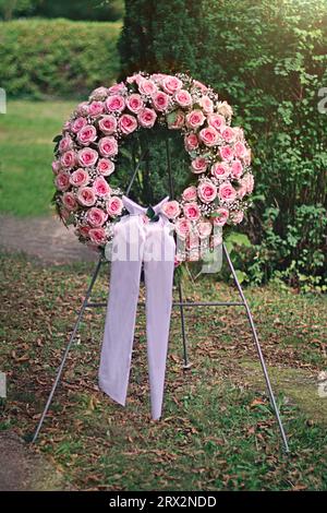 Pink funeral rose wreath on the cemetery. Stock Photo