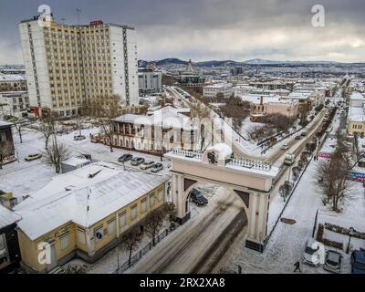 The old historic gate in the city center of Ulan-Ude, Republic of Buryatiya, Russia, with the Soviet architecture around during the winter day. Stock Photo