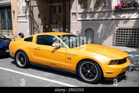 New York City, USA - August 05, 2023: 2011 Ford Mustang V6 yellow car passenger side view, parked Stock Photo