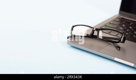 Glasses over laptop on blue background. Template for office and work projects. High quality photo Stock Photo