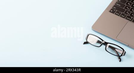 Glasses over laptop on blue background. Template for office and work projects. High quality photo Stock Photo