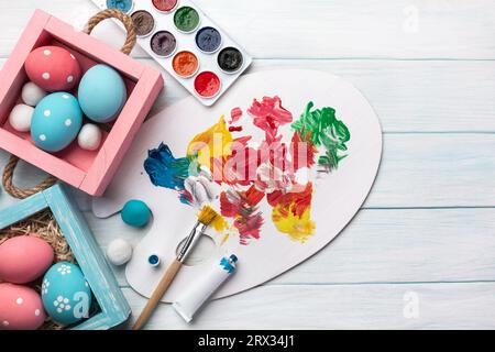 Easter background with colorful eggs, paints, brushes on stone gray. Top view with copy space. Stock Photo