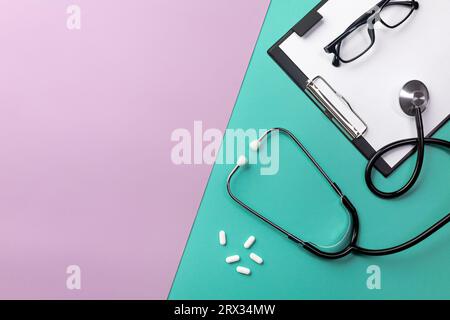 Stethoscope in doctors desk with tablet, glasses and pills. Top view with place for your text. Stock Photo