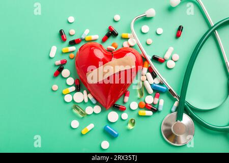 Heart broken pills and phonendoscope on turquoise background. High quality photo Stock Photo