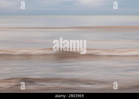 intentional camera movement of waves breaking on a beach in Worthing, West Sussex, UK Stock Photo