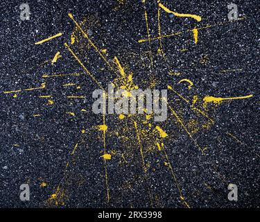 yellow paint splashes from spilt paint for road line markings on an asphalt pavement Stock Photo