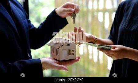 Male businessman or real estate agent holding house key for his client after signing contract in office. Stock Photo