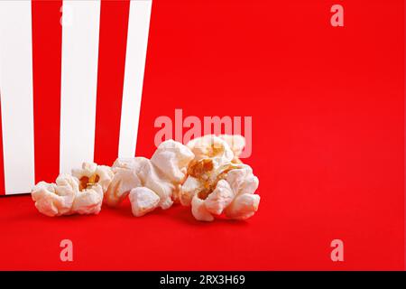 Glass with popcorn on a red background close-up Stock Photo