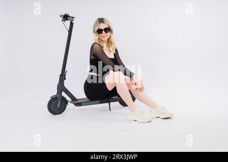 Full length profile shot of a female on an electric scooter isolated on white and red background Stock Photo