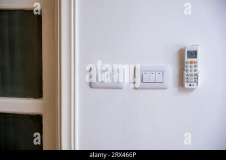 White House wall consist of electrical switches with Air conditioning remote Stock Photo