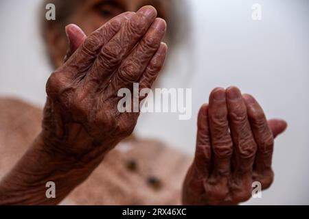 Old woman hands praying for god rising her hands Stock Photo