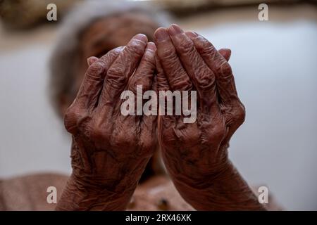 Old woman hands praying for god rising her hands Stock Photo