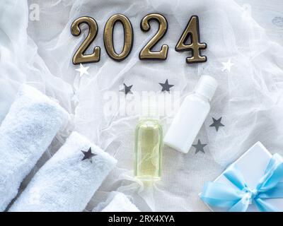 Christmas composition with 2024, towels, giftbox and body care products in bottles. New year Wellness card. Christmas, body and skincare concept. Hygi Stock Photo