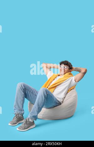 Young man sitting in beanbag on blue background Stock Photo