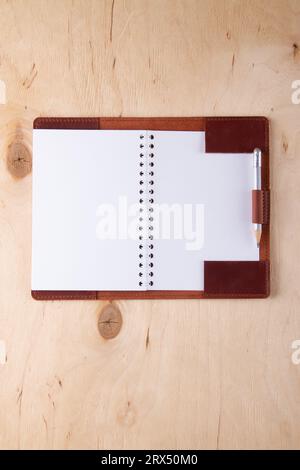 Blank writing-pad in leather cover with graphite pencil lie on wooden desk Stock Photo