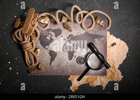 World map with travel equipment, airplane toy and golden nuggets on grunge black background Stock Photo