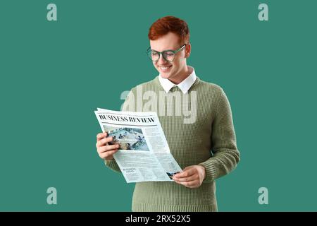 Young business owner reading newspaper on green background Stock Photo