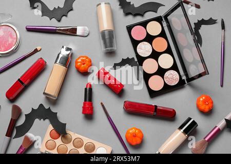 Composition with different cosmetic products, makeup brushes and Halloween decorations on grey background Stock Photo