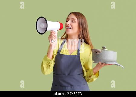 Young woman with chicken soup shouting into megaphone on green background Stock Photo