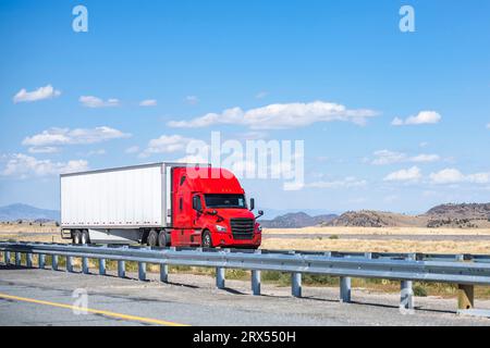 Industrial long hauler carrier red big rig semi truck tractor with high cab for truck driver rest transporting commercial cargo in dry van semi traile Stock Photo