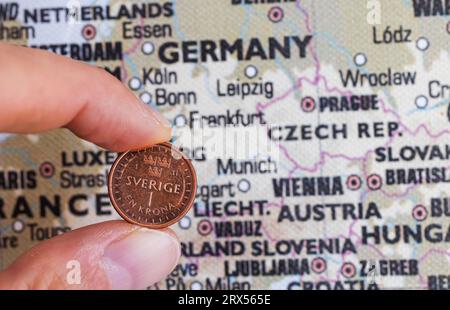 The Swedish krona is at a record low in relation to the euro. This week saw a new historic record low for the Swedish krona. This year alone, it has lost roughly 7 percent in value against the euro. Here when someone holds a Swedish krona in front of a map of Europe. Stock Photo