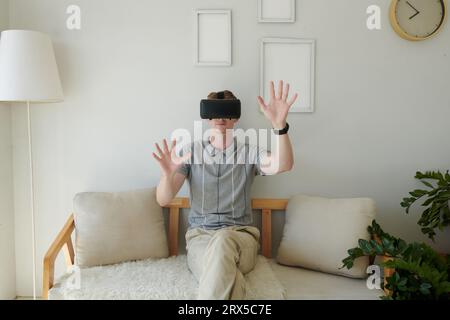 Young man in virtual reality headset touching invisible objects Stock Photo