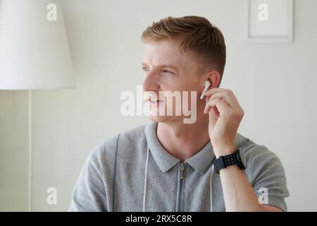 Young man wearing earbuds when calling coworker Stock Photo