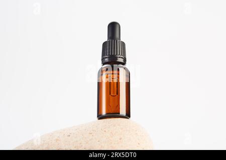 Brown dropper bottle without label is on light stone. Stock Photo