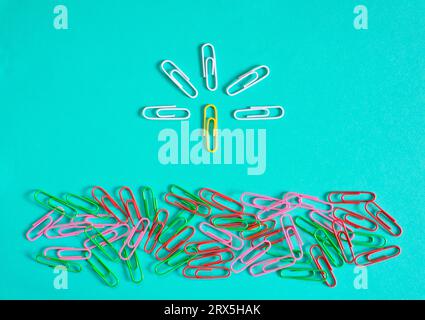 Business concept,team leader, different thinking and innovation. Simplistic flat lay with group of paper clips and one standing out from the crowd Stock Photo