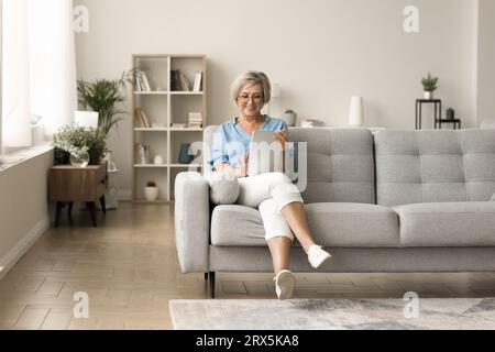 Happy pretty elderly mature woman using tablet computer Stock Photo