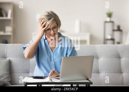 Mad concerned older retired woman in glasses getting financial problems Stock Photo