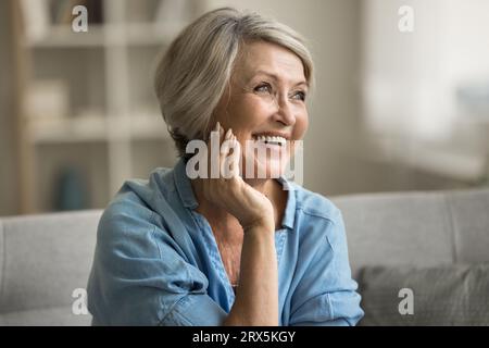 Happy beautiful blonde older mature lady touching facial skin Stock Photo
