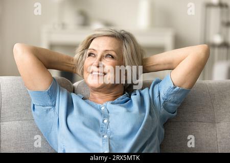 Positive pretty elderly mature woman relaxing on home couch Stock Photo