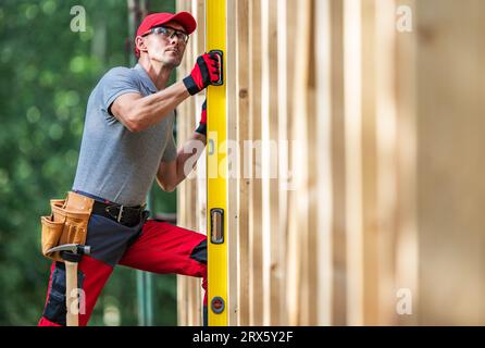 Construction Worker with Bubble Spirit Level Checking on Vertical Wooden Skeleton Frame Levels Stock Photo