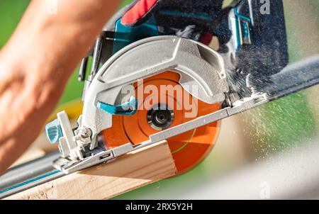 Construction Worker with Powerful Cordless Battery Operated Circular Saw in His Hands Stock Photo