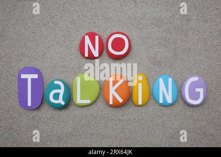 No Talking message composed with hand painted multi colored stone letters over natural beach sand Stock Photo