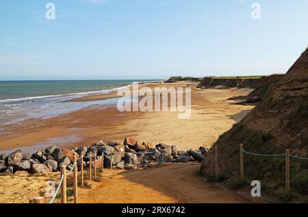 A view of the slipway down to a sandy beach by low cliffs on the North Norfolk coast in autumn at Happisburgh, Norfolk, England, United Kingdom. Stock Photo