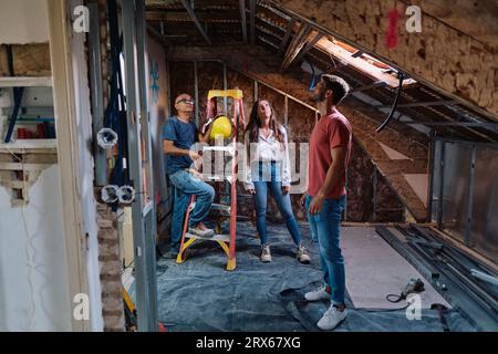 Man and woman having discussion with construction worker at construction site Stock Photo