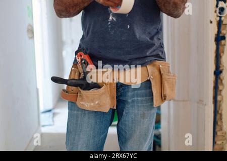 Construction worker wearing tool belt standing at site Stock Photo