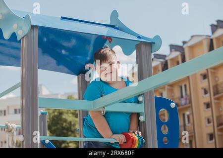 Smiling boy with down syndrome plays on playground Stock Photo