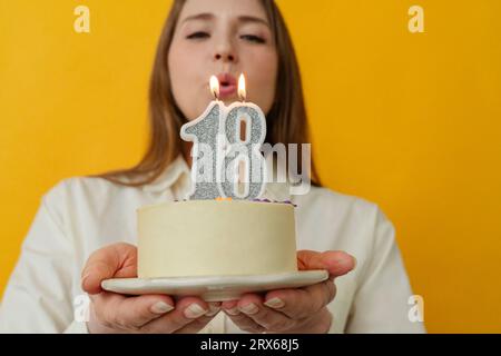 Woman blowing birthday candle on cake Stock Photo