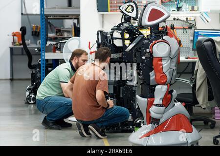 Perm, Russia - July 13, 2023: robotics engineers discussing work issues in a robot assembly workshop Stock Photo