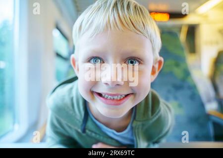 Happy blond boy traveling in train Stock Photo