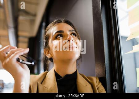 Smiling businesswoman day dreaming at office Stock Photo