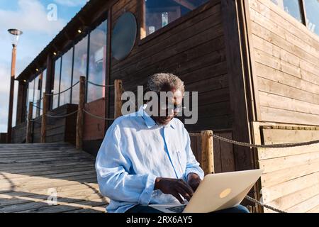 Engineer working on laptop in front of cafe Stock Photo