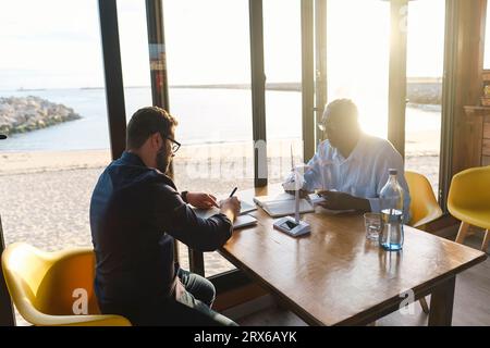 Engineers working and having discussion together in cafe Stock Photo