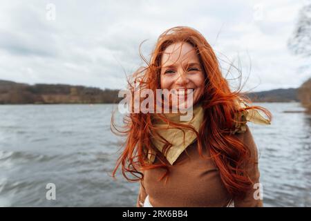 Happy redhead woman with hair blowing in wind Stock Photo